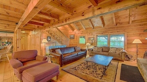 A wooden cabin interior with a staircase, two sofas, a coffee table, and a rug. - Log Cabin right next to entrance of the Great Smokey Mountains National Park! (Waynesville)