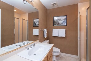 A modern bathroom with a large mirror, two sinks, a toilet, and a shower. - Cozy Condo steps to Coonskin lift (Telluride)