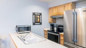 A modern kitchen with stainless steel appliances, wooden cabinets, and a built-in microwave. - Cozy Condo steps to Coonskin lift (Telluride)