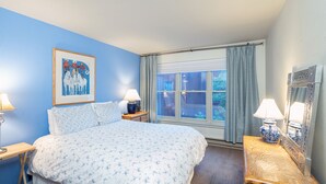 A bedroom with a large bed, two bedside tables, a window with curtains, and a painting on the wall. - Cozy Condo steps to Coonskin lift (Telluride)