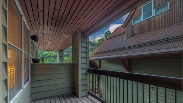 A wooden deck with a railing, a window with blinds, and a view of a mountain landscape. - Cozy Condo steps to Coonskin lift (Telluride)