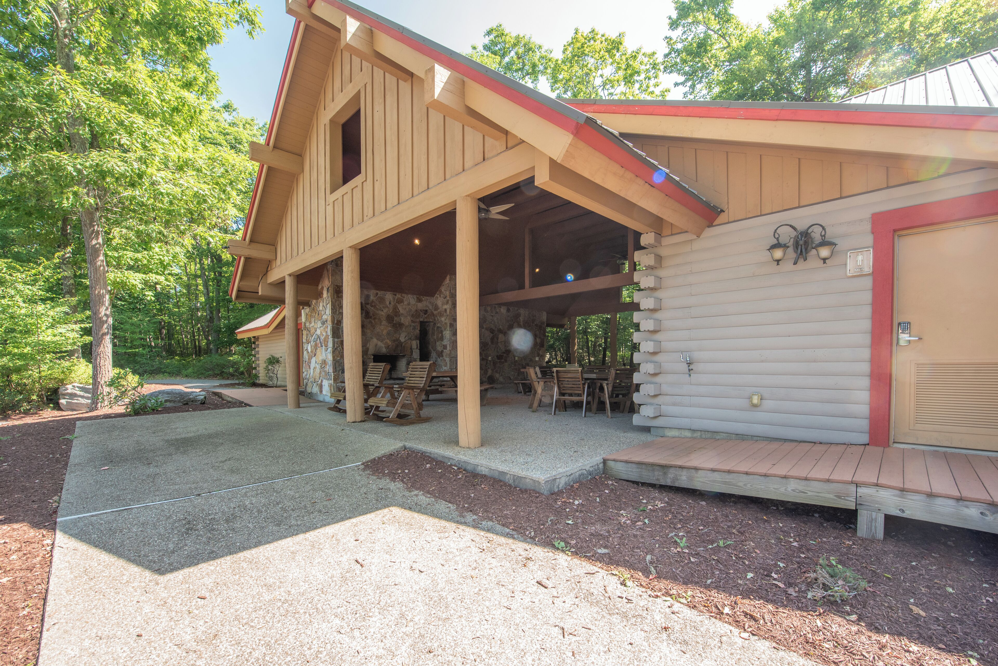 A wooden cabin with a covered porch, stone walls, and outdoor seating.