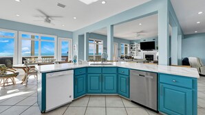 A modern kitchen with teal cabinets, white countertops, and a dishwasher.