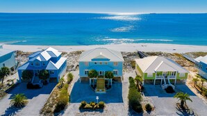 A beachfront property with three houses, a sandy beach, and the ocean.