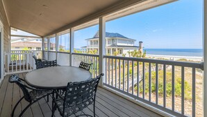 A covered outdoor area with a round table and chairs, overlooking a beach and houses. - Huge Oceanfront Home with Full Golf Membership (Georgetown)