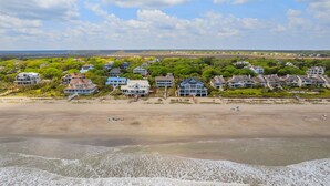 A coastal residential area with beachfront properties, including houses with large windows and balconies, and a sandy beach with a few people. - Huge Oceanfront Home with Full Golf Membership (Georgetown)
