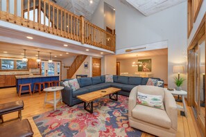 Relax in a spacious interior with a high ceiling and exposed beams, featuring a comfortable sofa and a casual dining area.
