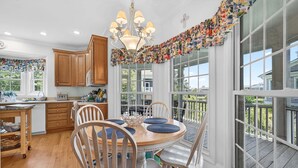 A kitchen with wooden cabinets, a dining table with chairs, a chandelier, and large windows with a view. - Inviting Beach Retreat with wonderful Lake Views to Relax and Enjoy (Georgetown)
