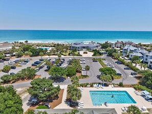 A resort with a swimming pool, parking lot, and ocean view.