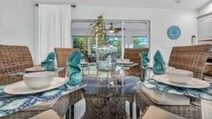 A dining area with wicker furniture, glass-top tables, and teal accents. - P27 - Private Beach Access! Pool home with everything you need for an unforgettable vacation. 3 bedroom 2 baths with deep water dockage. (Key Colony Beach)