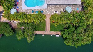 An aerial view of a resort with a swimming pool, lounge chairs, and a wooden deck. - P27 - Private Beach Access! Pool home with everything you need for an unforgettable vacation. 3 bedroom 2 baths with deep water dockage. (Key Colony Beach)
