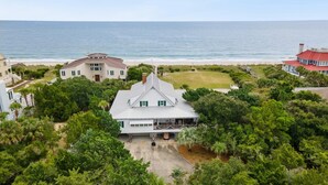Une propriété située sur la côte, comprenant une grande maison, un bâtiment plus petit et offrant une vue sur la plage.