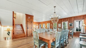 A spacious dining area with a large wooden table and chairs, a chandelier, and a staircase leading to another room. - Spectacular Oceanfront Living with an Inviting Kitchen Perfect for Entertaining Kitchens Beach House (Georgetown)