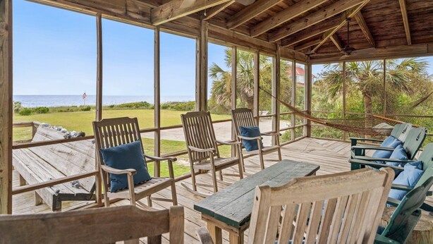 A covered outdoor seating area with wooden furniture and a view of the beach. - Spectacular Oceanfront Living with an Inviting Kitchen Perfect for Entertaining Kitchens Beach House (Georgetown)