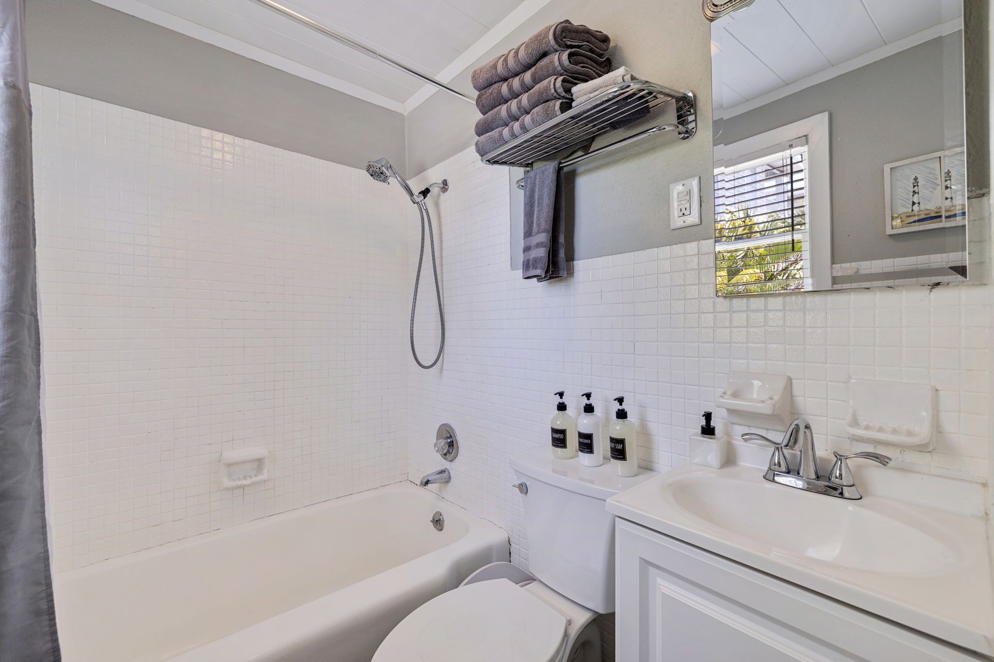 Un bagno con vasca, water, lavandino e porta asciugamani con asciugamani piegati.