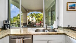 A kitchen with a large window, a coffee maker, and a sink. - Wailea Condo Near Keawakapu Beach with Pool & Tropical Setting (Wailea)