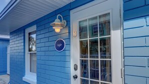 Uma casa azul com porta branca, uma janela pequena e uma luz de varanda.