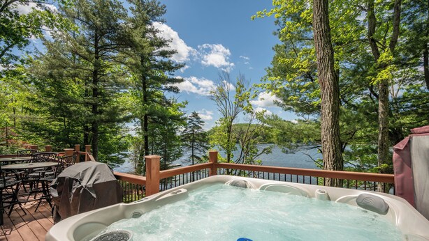 A hot tub on a deck with a view of a lake and trees.