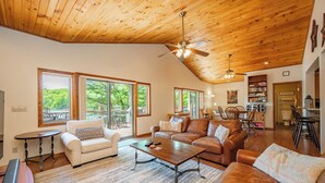 A spacious living area with a high ceiling, large windows, and a cozy seating arrangement.