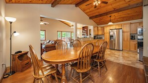 A spacious kitchen with wooden cabinets, a large dining table, and a ceiling fan.