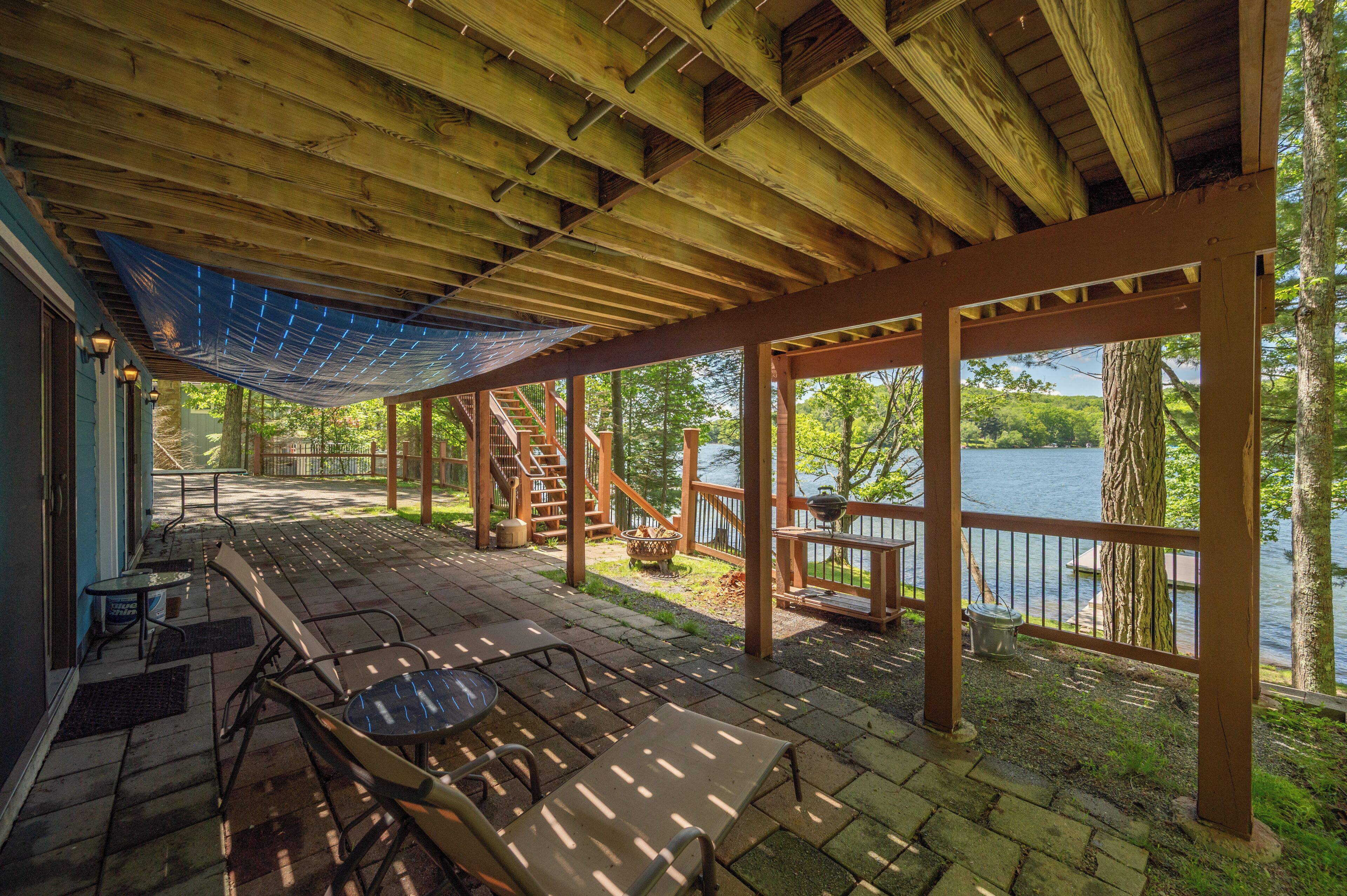 A covered outdoor deck with wooden railings, a table, and chairs.
