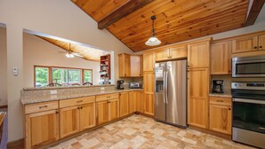 A kitchen with wooden cabinets, a stainless steel refrigerator, an oven, and a ceiling fan.