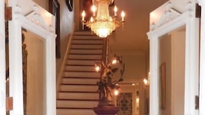 Eine prachtvolle Treppe mit einer Chandelier, weißen Türen und einem Holzboden.