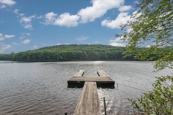 A wooden dock extending into a calm lake with a forested hill in the background. - Rustic Chalet w/ Fireplaces & Jetted Tub (McHenry)