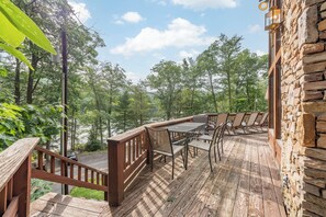 A wooden deck with a table and chairs, overlooking a forested area. - Rustic Chalet w/ Fireplaces & Jetted Tub (McHenry)