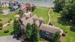 An aerial view of a residential area with houses, a lake, and boats. - Luxury Lake Escape w/ Indoor Pool & Hot Tubs (Swanton)