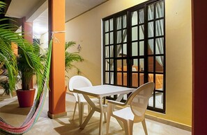 Enjoy a peaceful moment in this serene outdoor space with a table for two, a view of a wooden structure, and lush greenery.