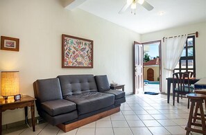 Relax in this stylish living room with a sofa, dining area, and pool views.