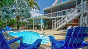 A pool area with blue chairs, a covered seating area, and a staircase leading to a building with a white railing. - P78 - Charming 3 bedroom 2 bath home in Sombrero Beach with dock and pool (Marathon)