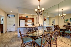 A spacious kitchen with a dining area, featuring a large island, wooden chairs, and a chandelier.