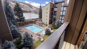 Edificio residencial con piscina, mobiliario exterior y vista a una montaña nevada.