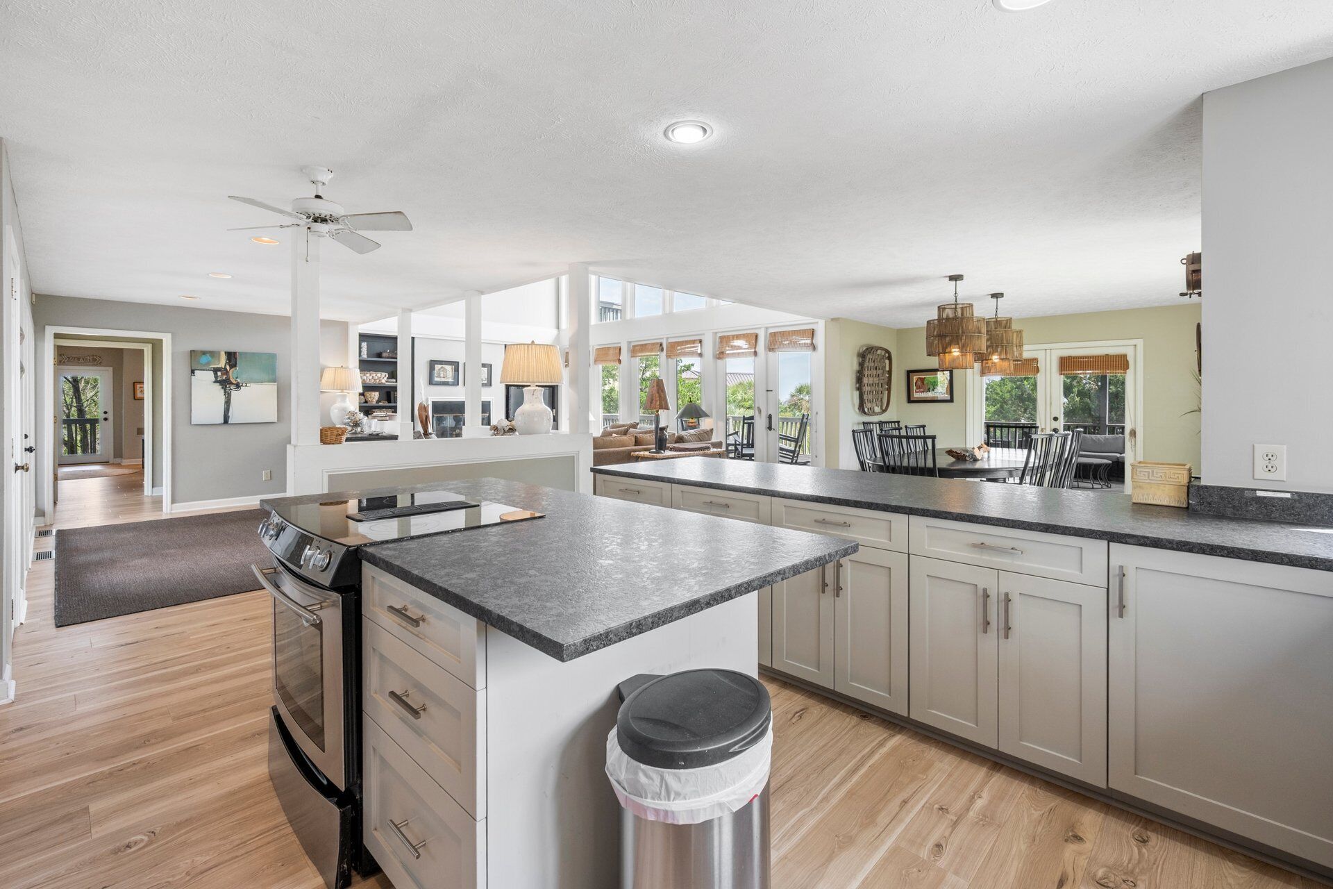 A spacious kitchen with a large island, wooden flooring, and a view of the outdoors.