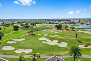 Un parcours de golf avec des bunkers, un plan d’eau et des immeubles résidentiels en arrière-plan.