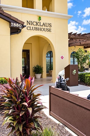 Exterior do Nicklaus Clubhouse, com entrada visível, um vaso de planta e uma pequena estátua.