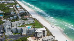 Vista aérea de un hotel costero con varias edificaciones, una playa y una piscina.