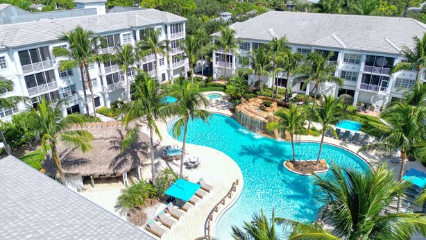 A resort with multiple buildings, a large swimming pool, and palm trees. - Relax In This Poolside Paradise! (Bonita Springs)