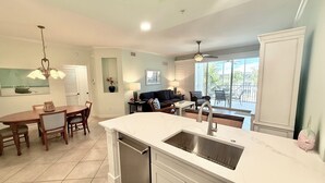 A modern kitchen with a large island, stainless steel appliances, and a dining area with a table and chairs. - Tropical Poolside Getaway! (Bonita Springs)