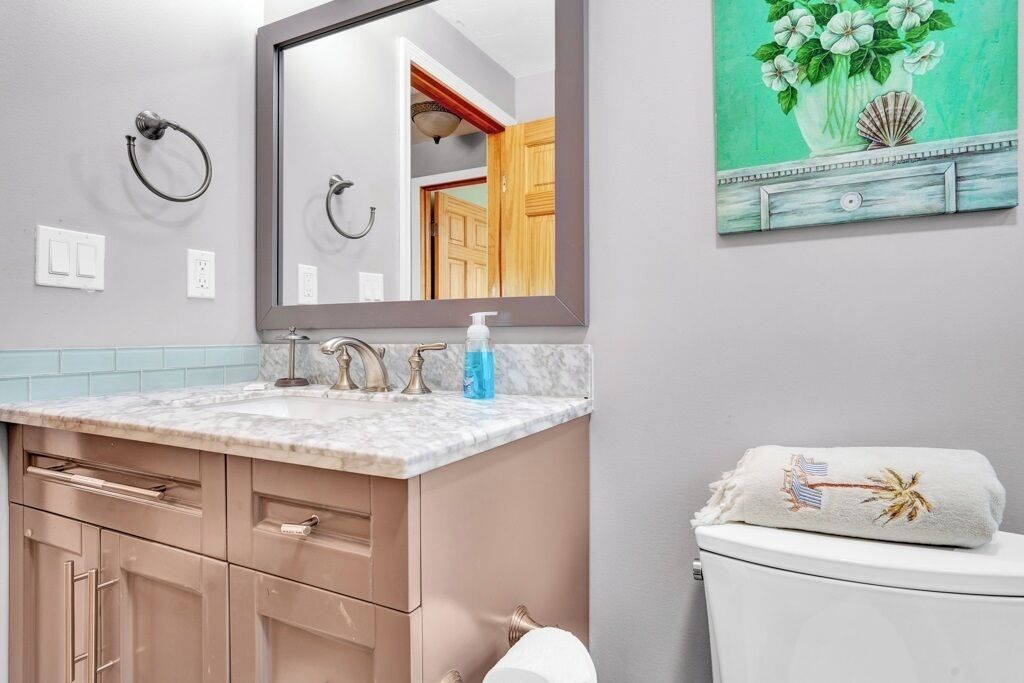 A bathroom with a marble sink, a towel on the toilet, and a mirror reflecting a wooden door.