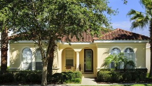 A single-story house with a tiled roof, a front porch, and a small garden.