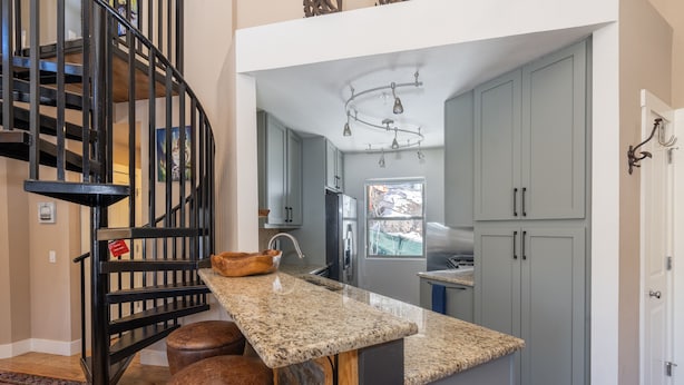 Una cocina con encimera de granito, estufa integrada y refrigerador de acero inoxidable.