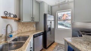 Una cocina moderna con encimeras de granito, electrodomésticos de acero inoxidable y armarios de color gris claro.