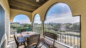 A balcony with a wooden table and chairs, a bench, and a view of a residential area with houses and trees. - Second Row, Steps away from the Ocean, Pool Table, Large Sun Deck (Georgetown)