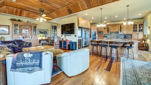 A spacious living room with a fireplace, a dining area with bar stools, and a kitchen with wooden cabinets and a large island. - Second Row, Steps away from the Ocean, Pool Table, Large Sun Deck (Georgetown)