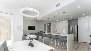 Una cocina moderna con una isla central, taburetes de bar y un comedor con mesa y sillas.