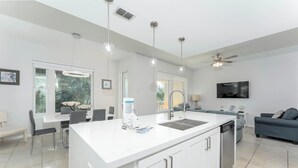 Una cocina moderna con una isla central, armarios blancos e iluminación colgante.