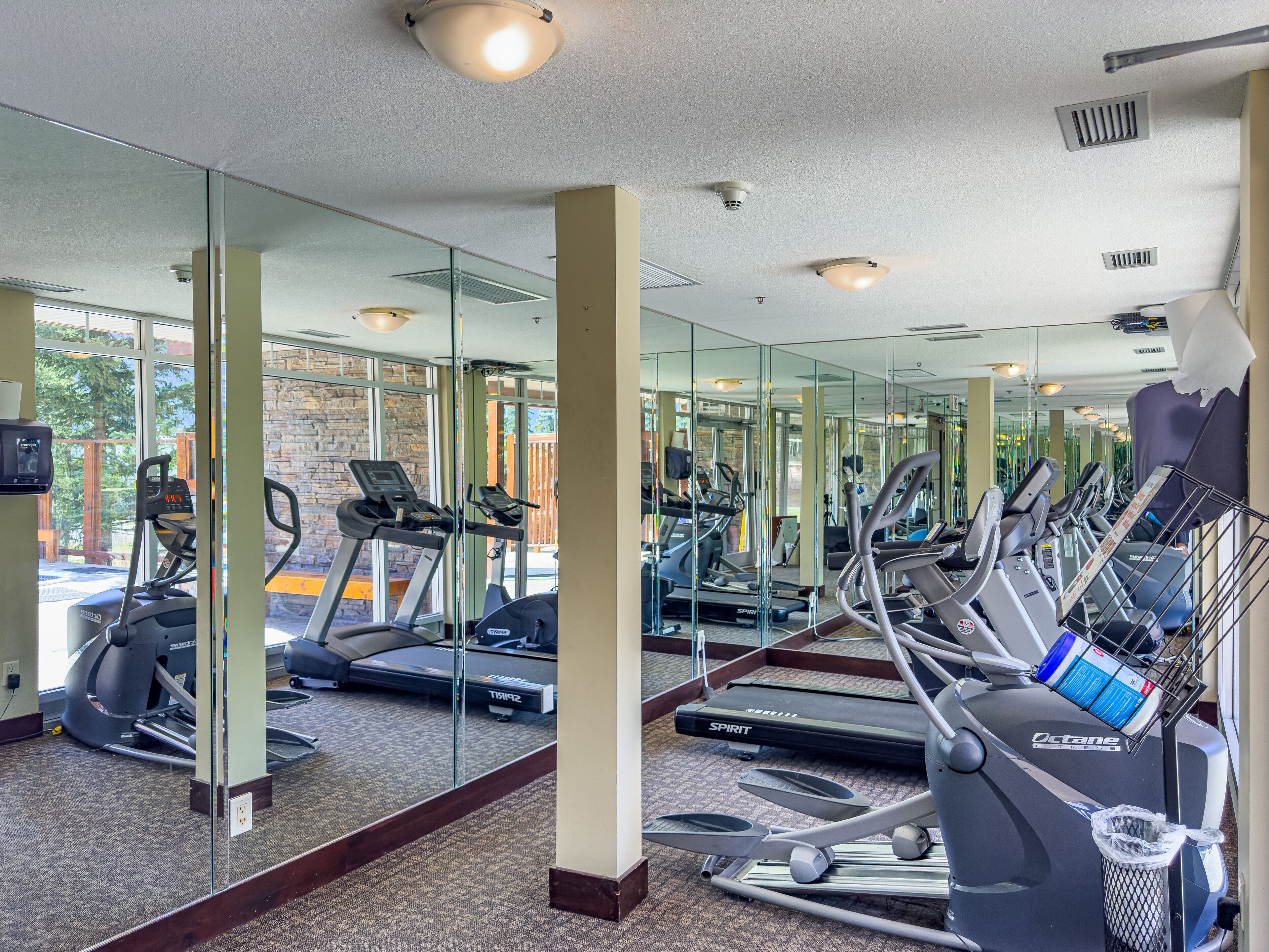 A gym with multiple treadmills, exercise bikes, and a mirrored wall.